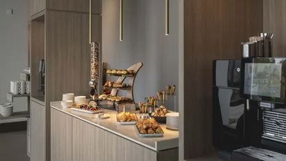 Frühstücksbuffet mit Gebäck, Müsli, Tellern und Kaffeemaschine