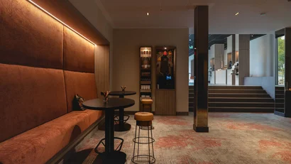 Moderner Cafébereich mit braunen Sitzbänken und Barhockern