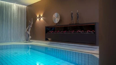 Modernes Schwimmbad mit Kamin und dekorativen Skulpturen an der Wand