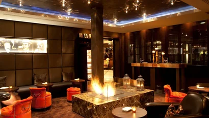 Elegante Lounge mit Kamin, roten Sesseln und warmem Licht