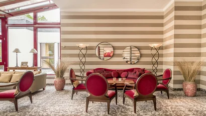 Elegantes Wohnzimmer mit rotem Sofa und Stühlen vor gestreifter Wand